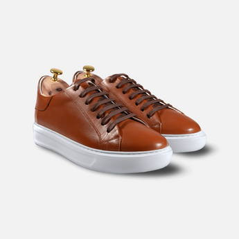 Front angle view of Shoescoo’s burnt orange Elegante Sneaker made with full-grain leather, showcasing its sleek silhouette and white outsole.