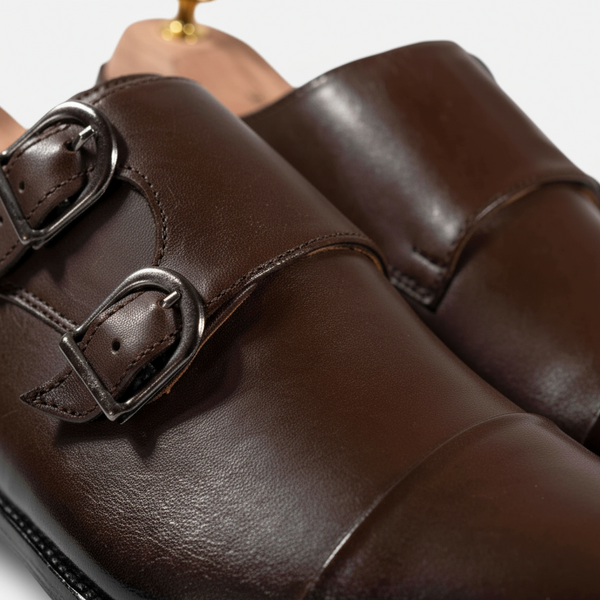 Close-up of brown double monk strap shoe buckles — full-grain leather and handcrafted detailing.
