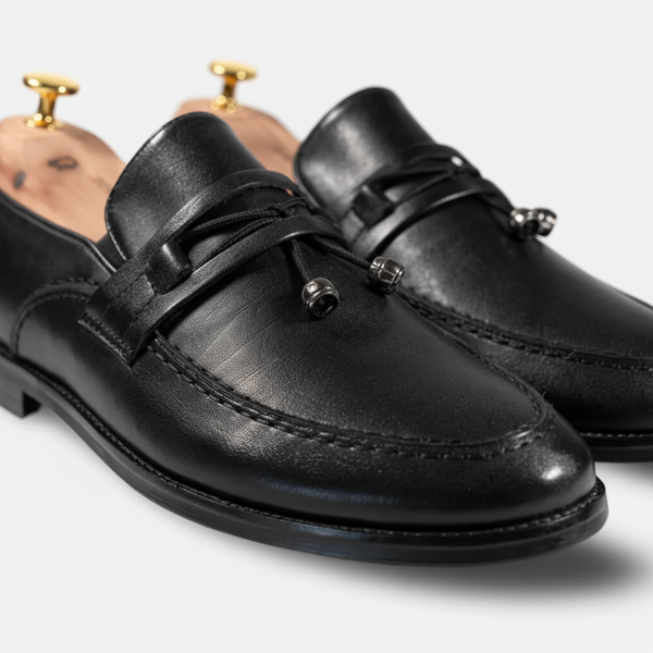 Close-up detail of Aurora black tassel loafers with shoe trees inserted, showing high-quality full-grain leather and tassel design.
