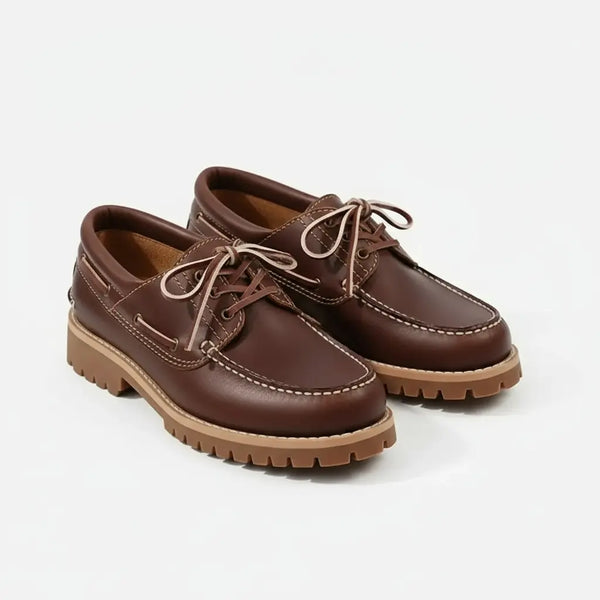 Close-up of brown leather boat shoes — full-grain leather and hand-stitched moc-toe details.
