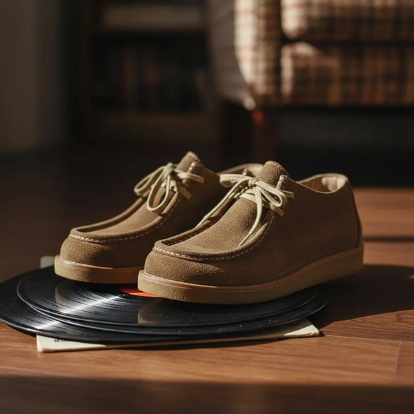 Handcrafted khaki suede moc toe boots in a cozy interior setting — laid-back sophistication.
