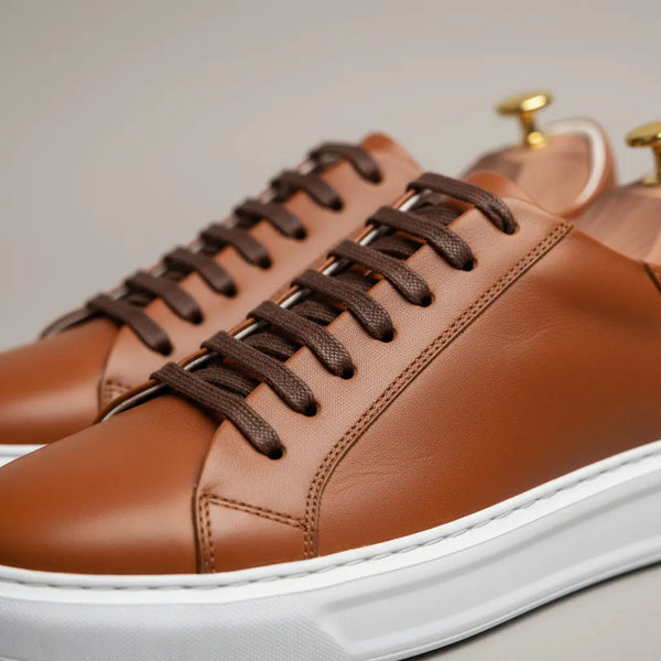 Side profile of tan leather sneakers with clean low-top design and sculpted sole — men’s casual sneakers for office and travel.