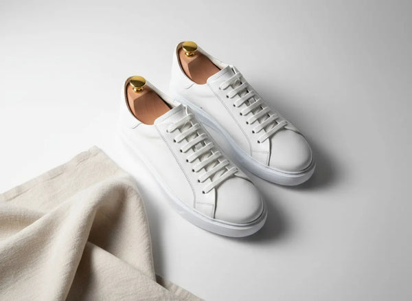Close-up of men’s white leather sneakers showing smooth full-grain texture and hand-finished details — minimalist handcrafted dress sneakers.